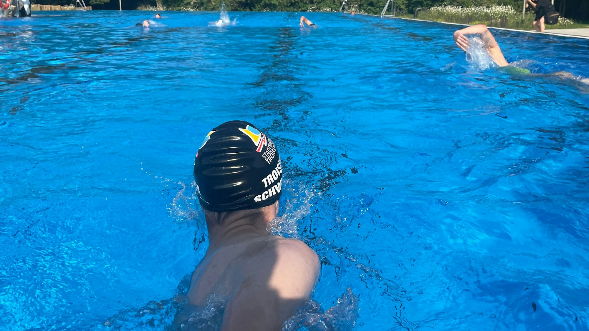 Menschen schwimmen in einem Außenbecken.