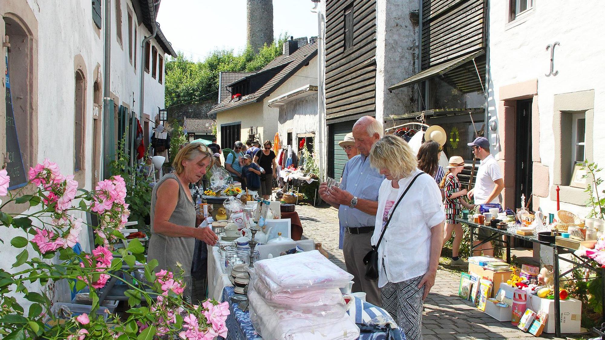 Das Foto zeigt eine Gasse mit mehreren Ständen, an denen Besucher sich umschauen.