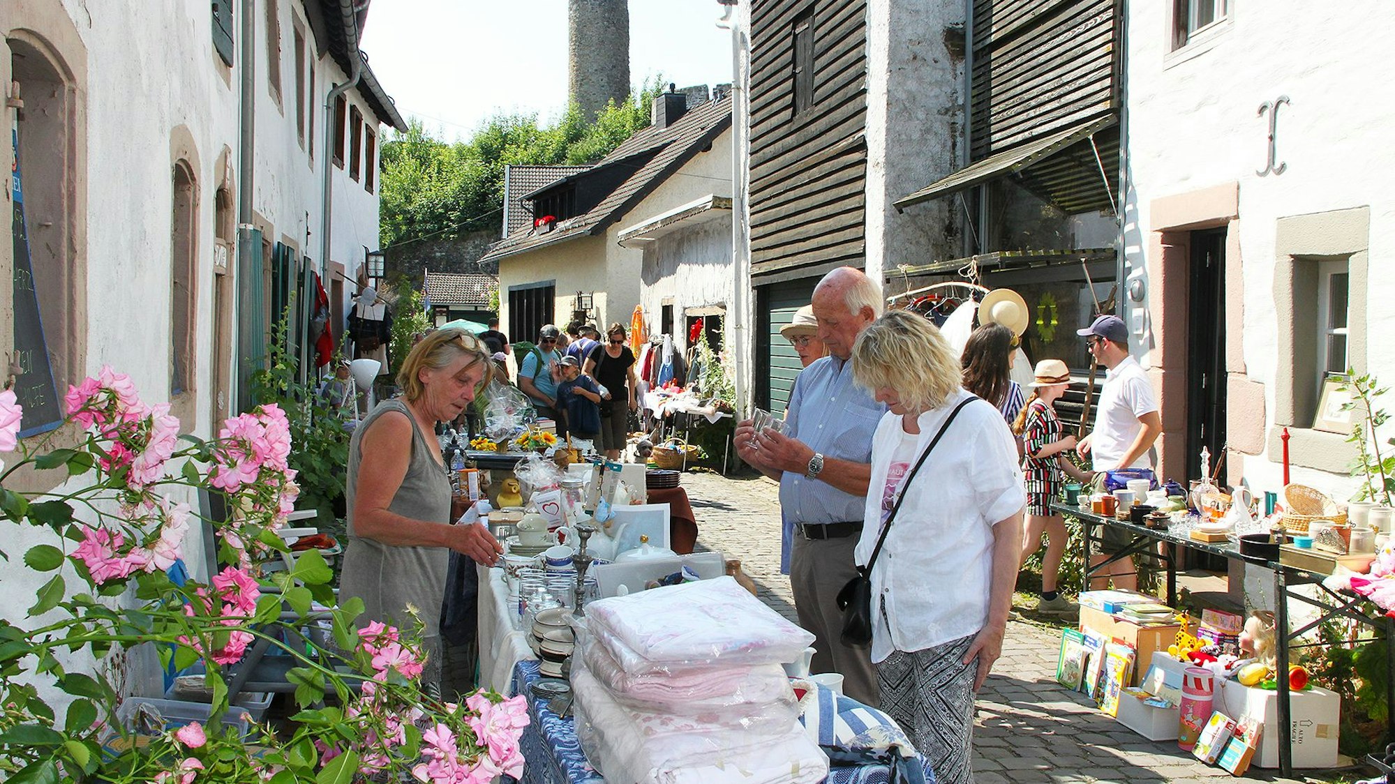 Das Foto zeigt eine Gasse mit mehreren Ständen, an denen Besucher sich umschauen.