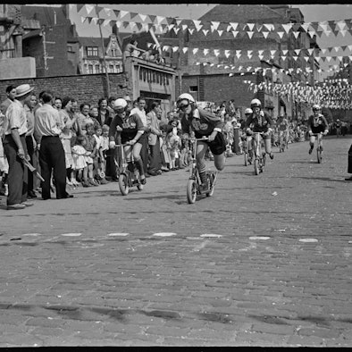 In der Kölner Südstadt nutzen die Menschen das Wetter im Sommer 1955 für ein Rollerrennen.