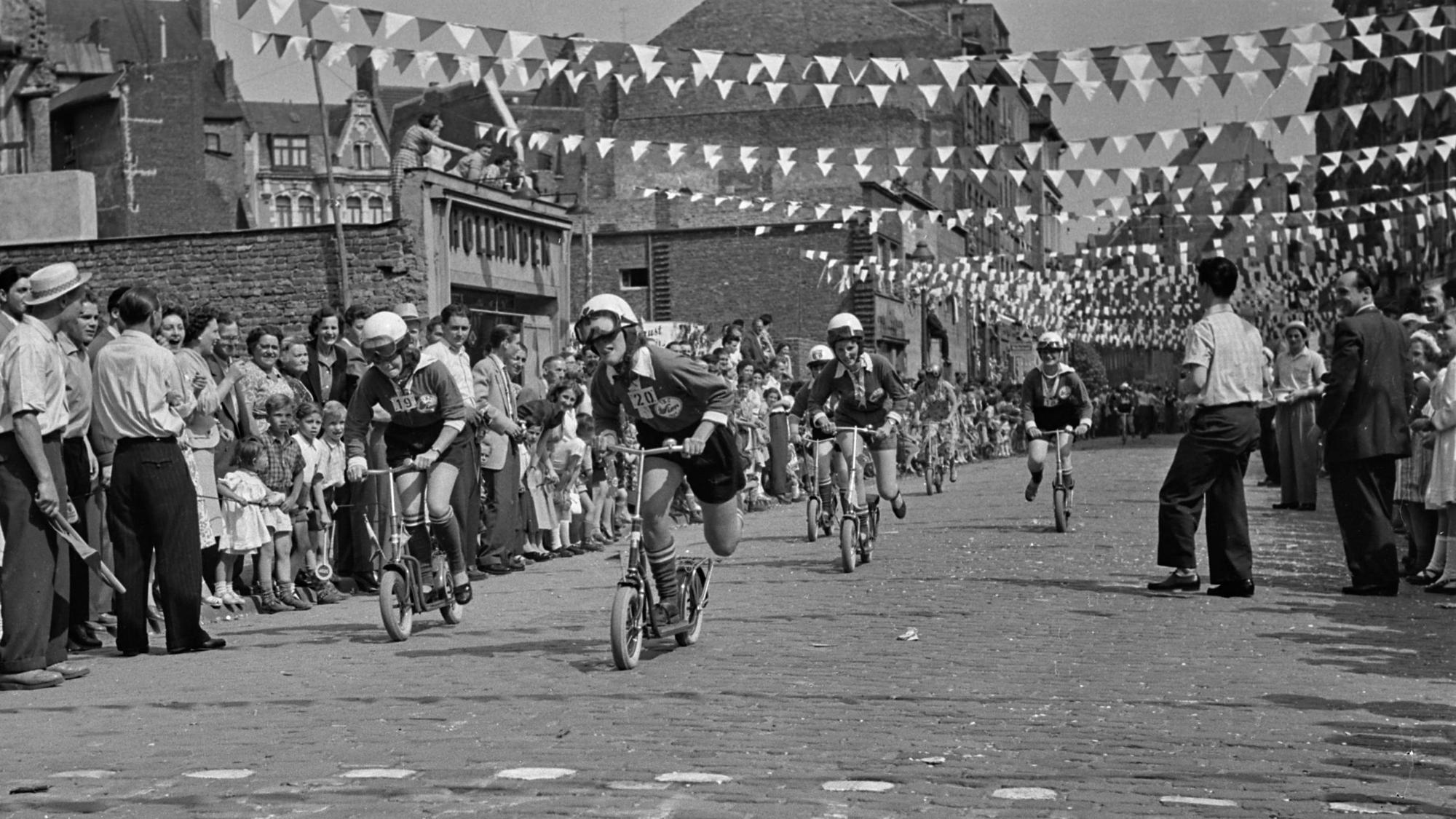 In der Kölner Südstadt nutzen die Menschen das Wetter im Sommer 1955 für ein Rollerrennen.