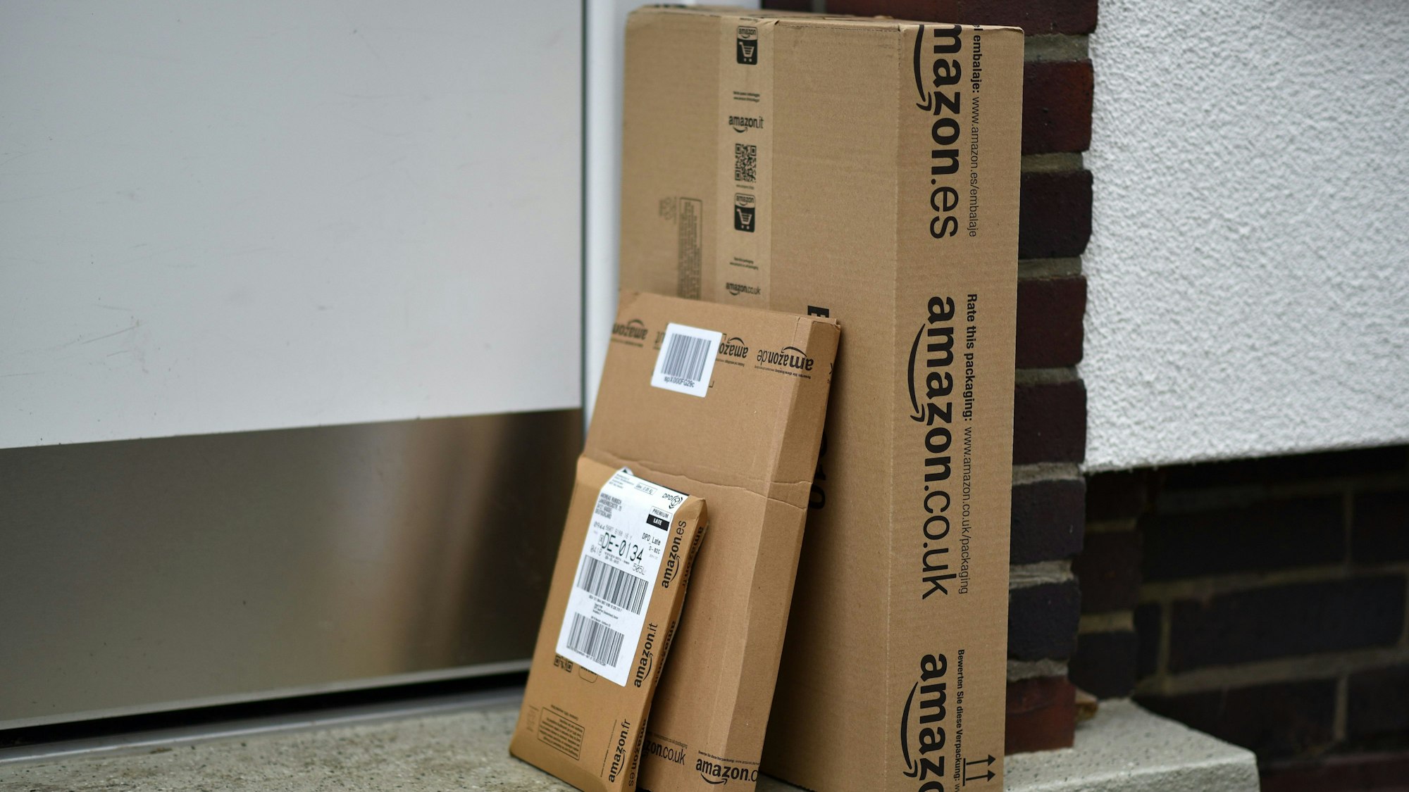 Päckchen des Online-Versandhändlers Amazon stehen vor einer Haustür. Deutschlands Paketbranche setzt immer stärker darauf, die Sendungen bei der Zustellung nur vor die Tür zu legen und nicht mehr zu übergeben. Die Anzahl sogenannter Abstell-Genehmigungen stieg in den vergangenen Jahren bei den verschiedenen Paketfirmen stark an.
