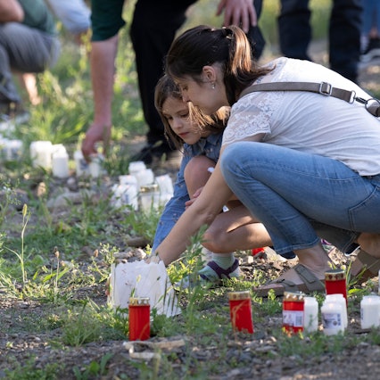 Zum Gedenken an die Todesopfer der Flutkatastrophe entzünden Menschen am Ufer der Ahr im Dorf Schuld Kerzen.