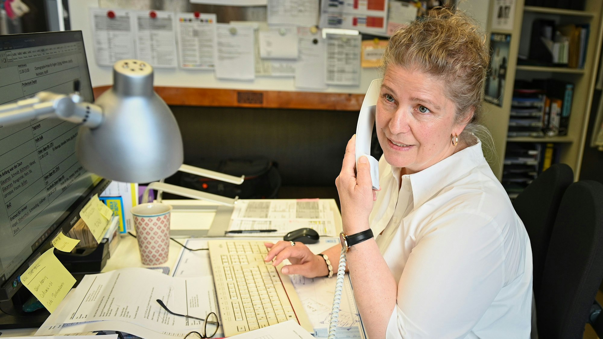 Sabine Döring
sitzt an einem Schreibtisch, mit der einen Hand tippt sie auf eine Tastatur und mit der anderen hält sie einen Telefonhörer.