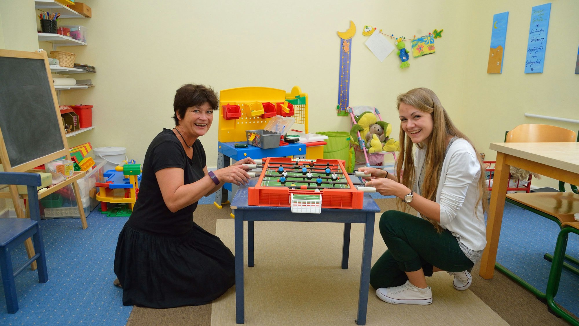 Katrin Fassin und Annika Nern vom Kinderschutzbund sitzen an einem mobilen Tischkicker im Spielraum.
