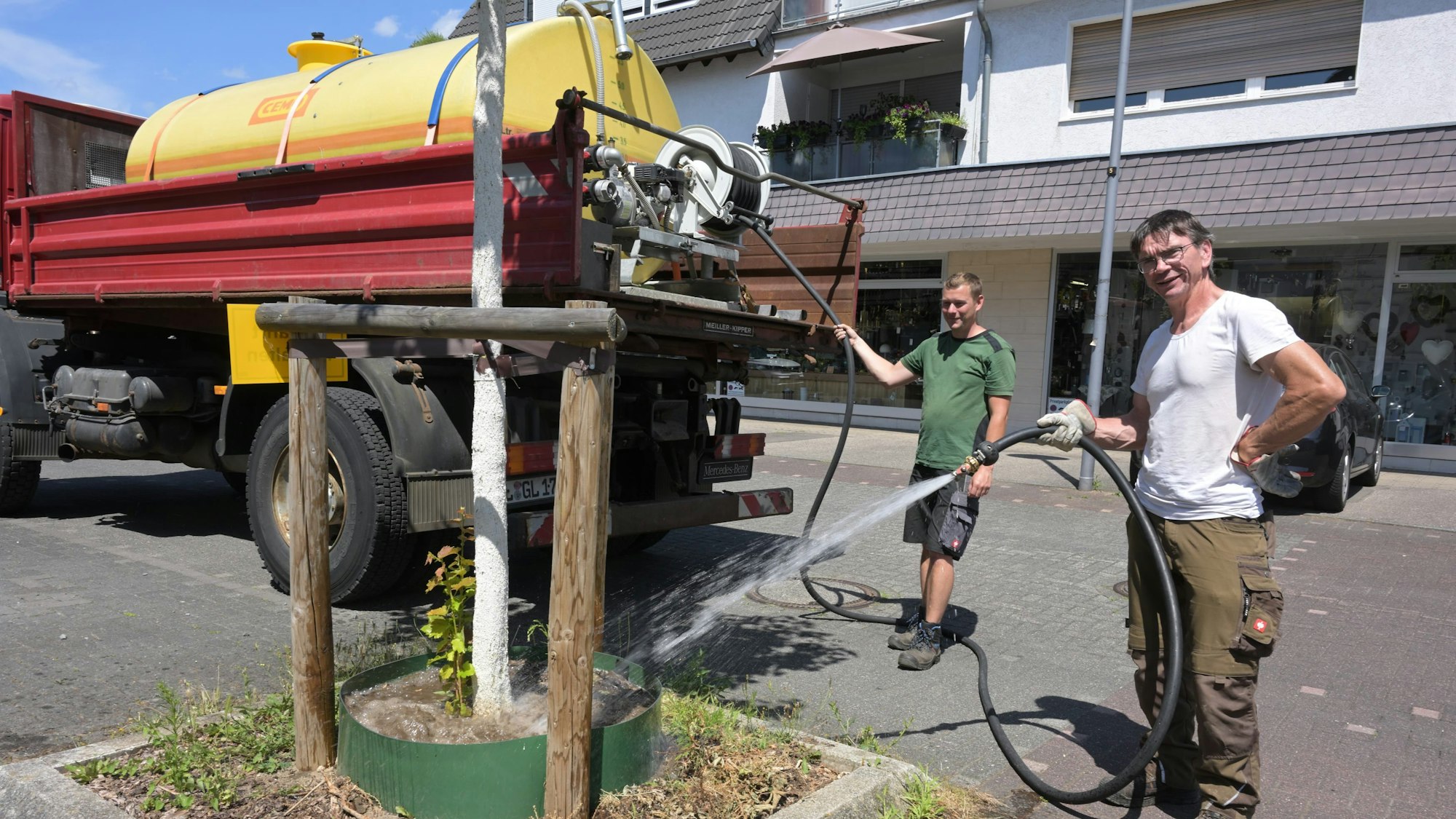 Mitarbeiter der Stadt gießen Straßenbäume.