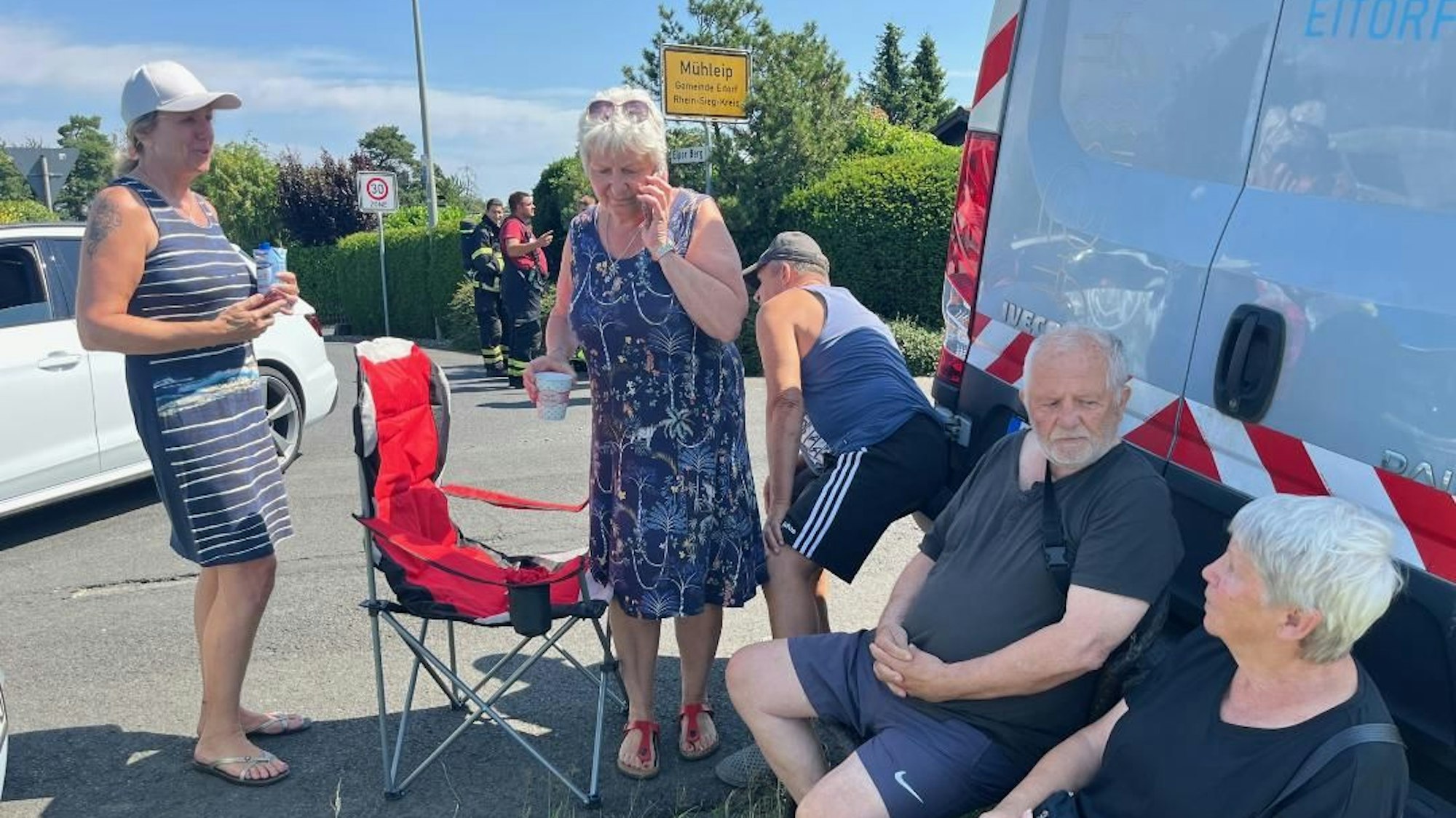 Anwohner sitzen auf einer Straße.