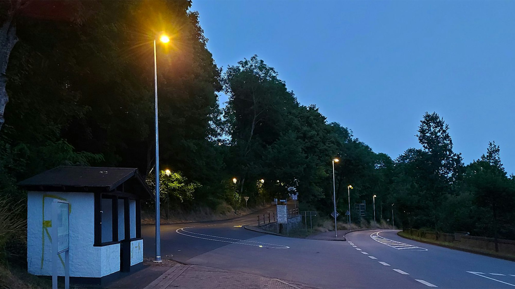 Das Bild zeigt die Ortsdurchfahrt Kronenburg in der Abenddämmerung. Die neuen Straßenlampen sind bereits eingeschaltet.