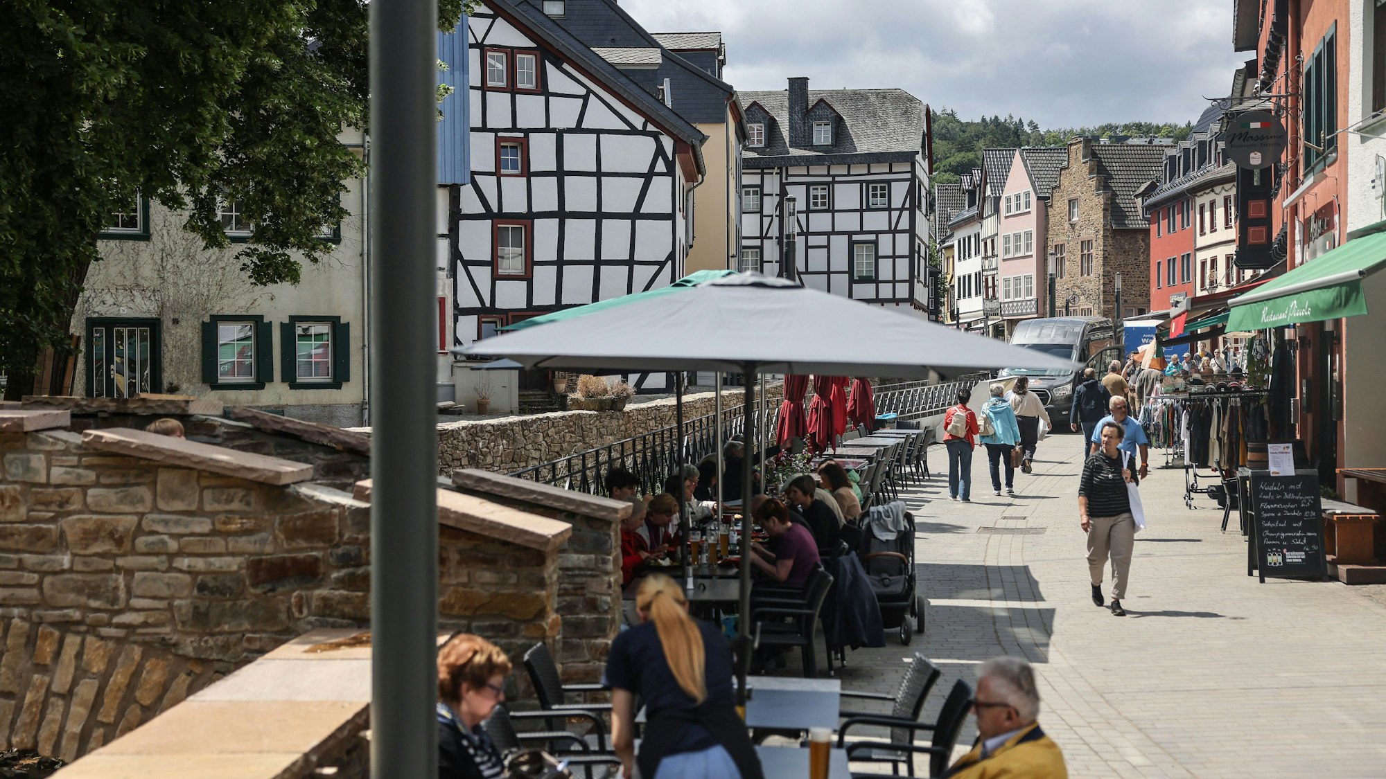 Menschen sitzen in der Fußgängerzone in einem Straßencafé.