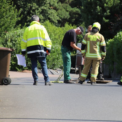 Feuerwehrleute begutachten einen Kanalschacht.
