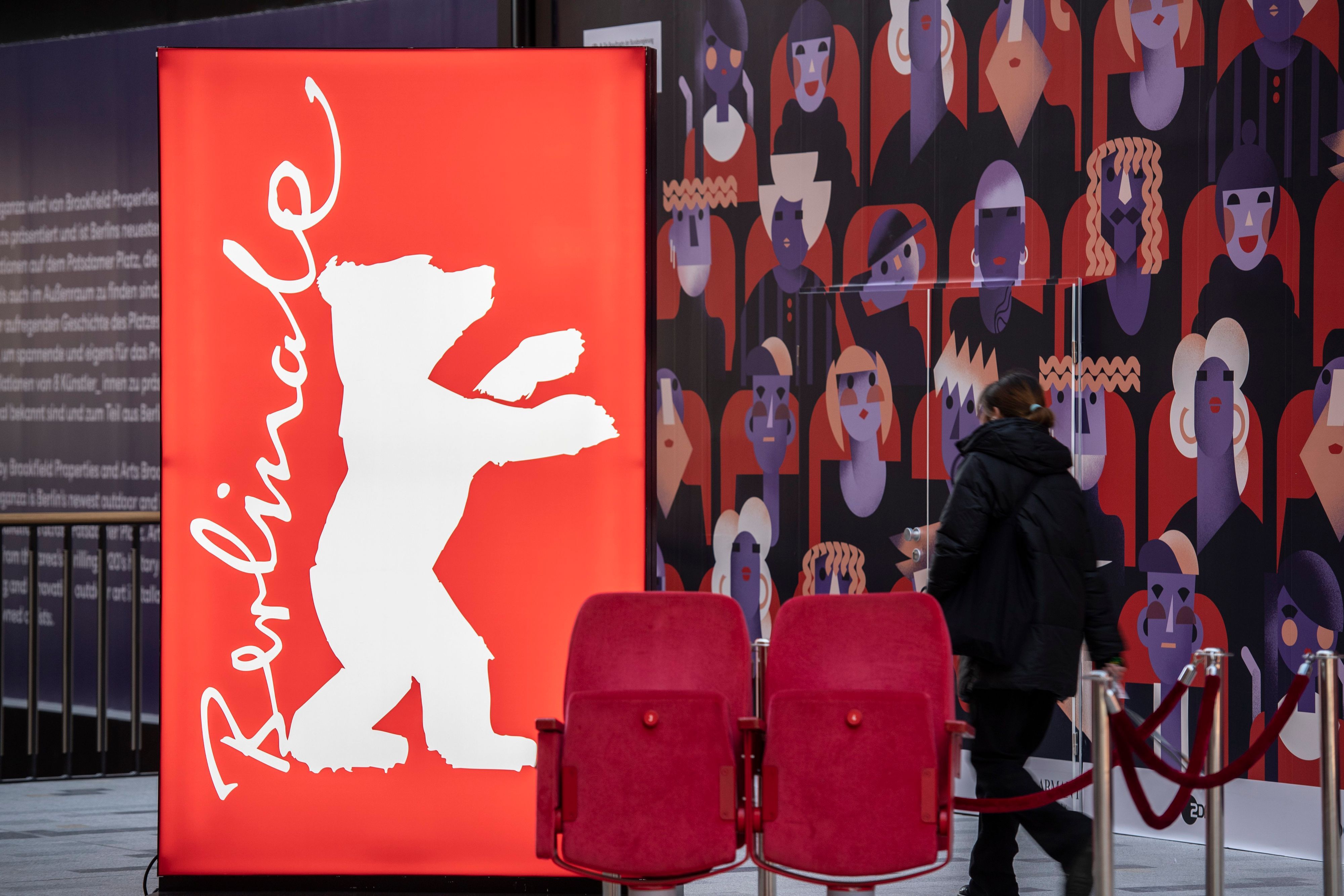 Eine Frau geht am Logo der Filmfestspiele Berlinale vorbei.