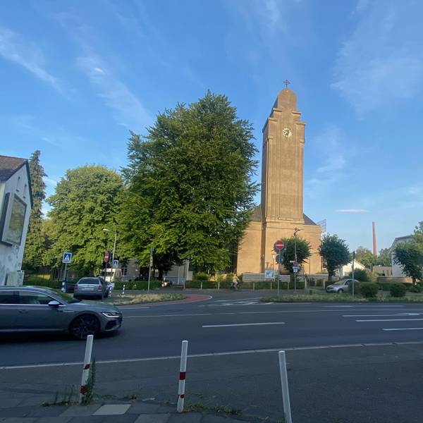 An einer mehrspurigen Straße ist frontal ein Kirchengebäude zu sehen.