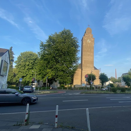 An einer mehrspurigen Straße ist frontal ein Kirchengebäude zu sehen.