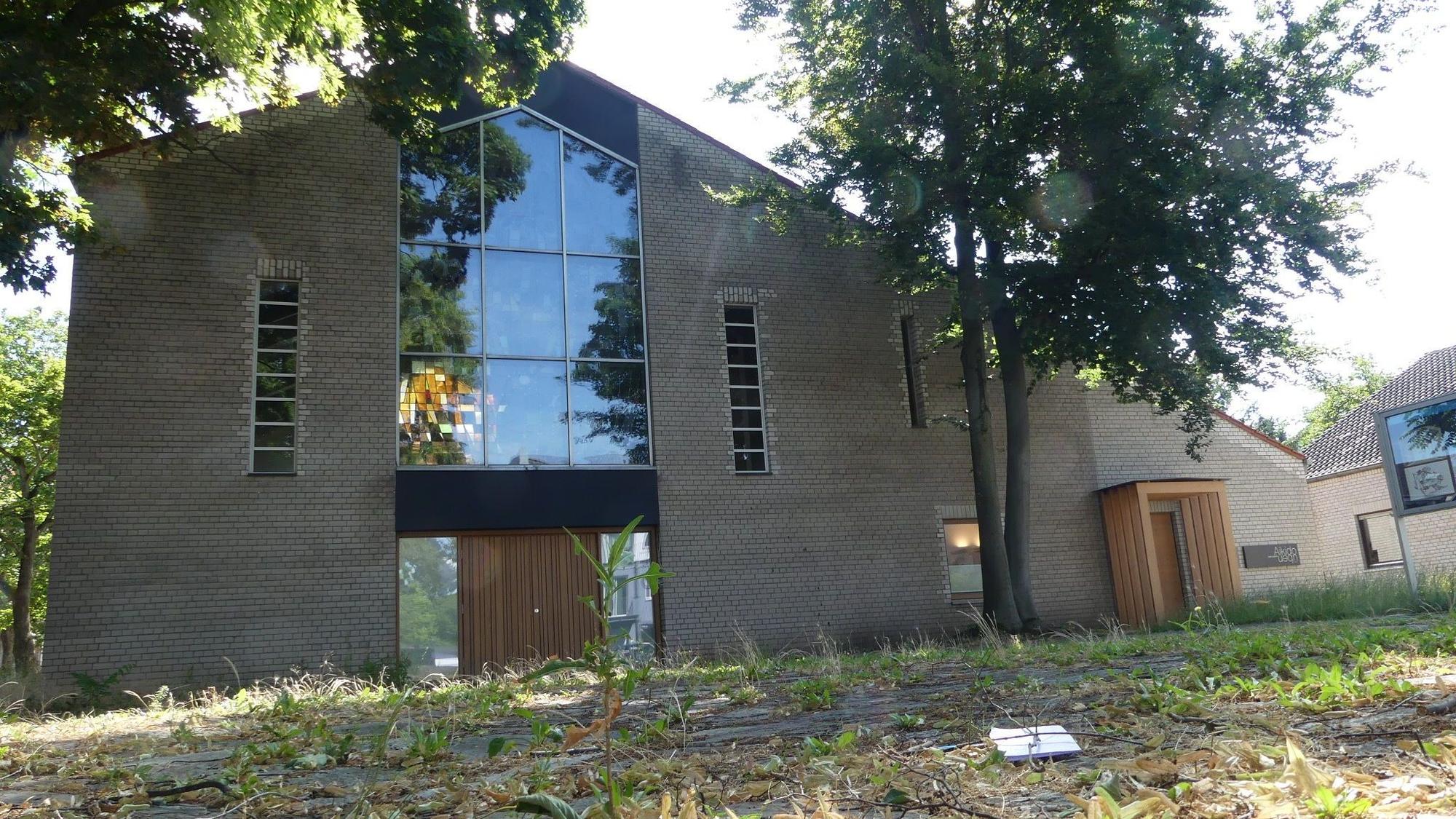 Ein von Unkraut überwucherter Platz vor einem Kirchengebäude ist zu sehen.