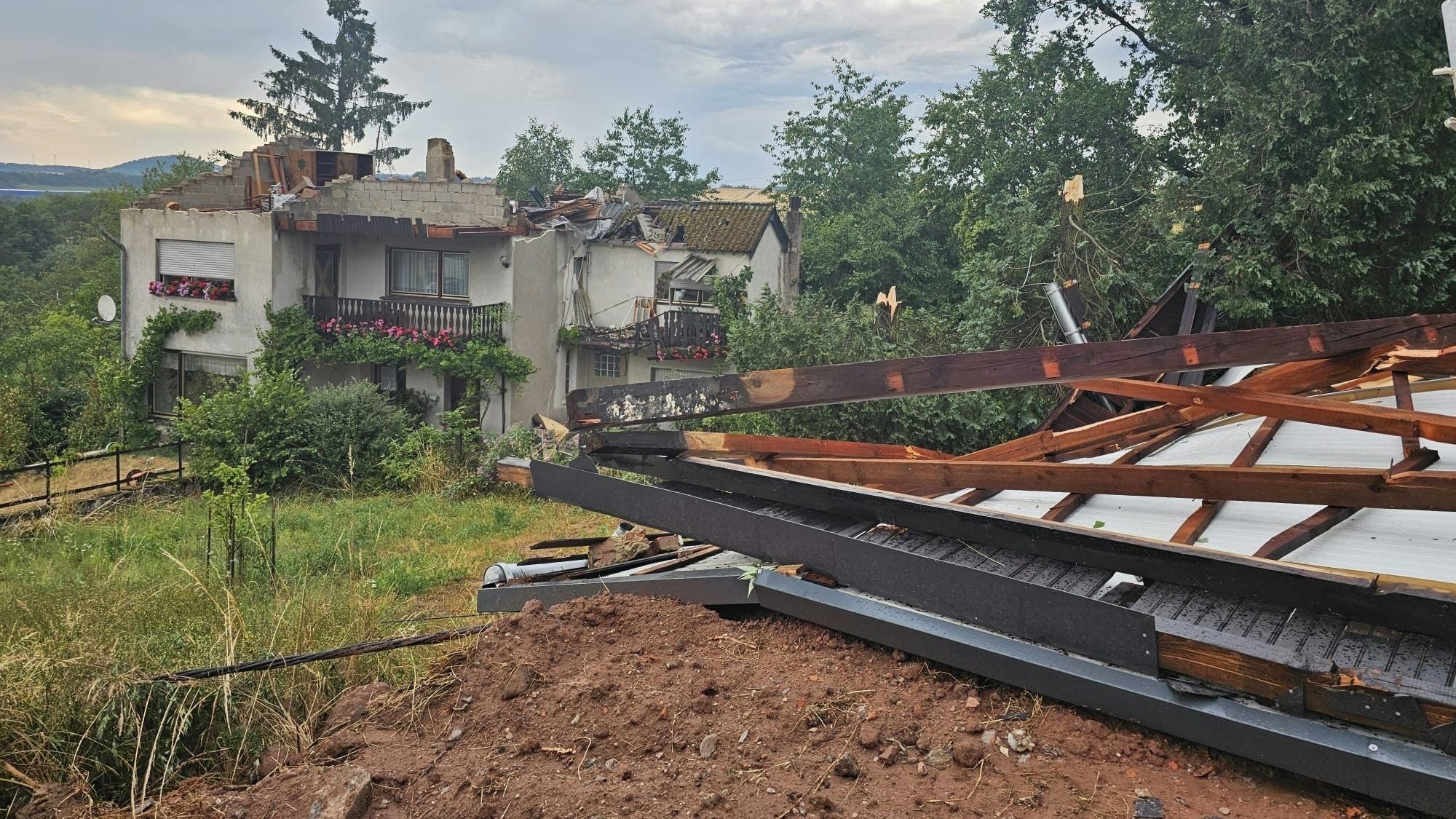 Ein Blick auf stark beschädigte Hausdächer nach einem Unwetter in Asweiler der saarländischen Gemeinde Freisen im Landkreis St. Wendel.