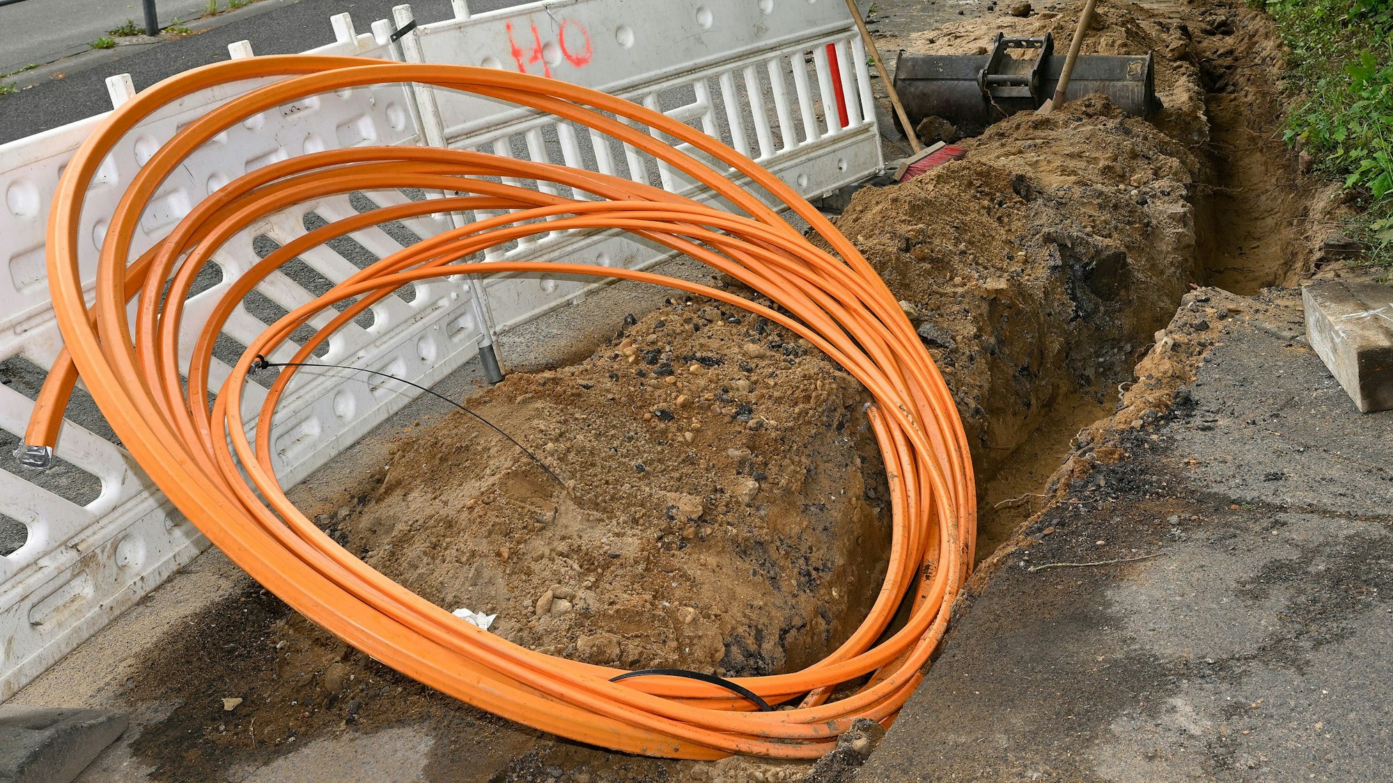 Ein Glasfaserkabel liegt vor einem Bauzaun.