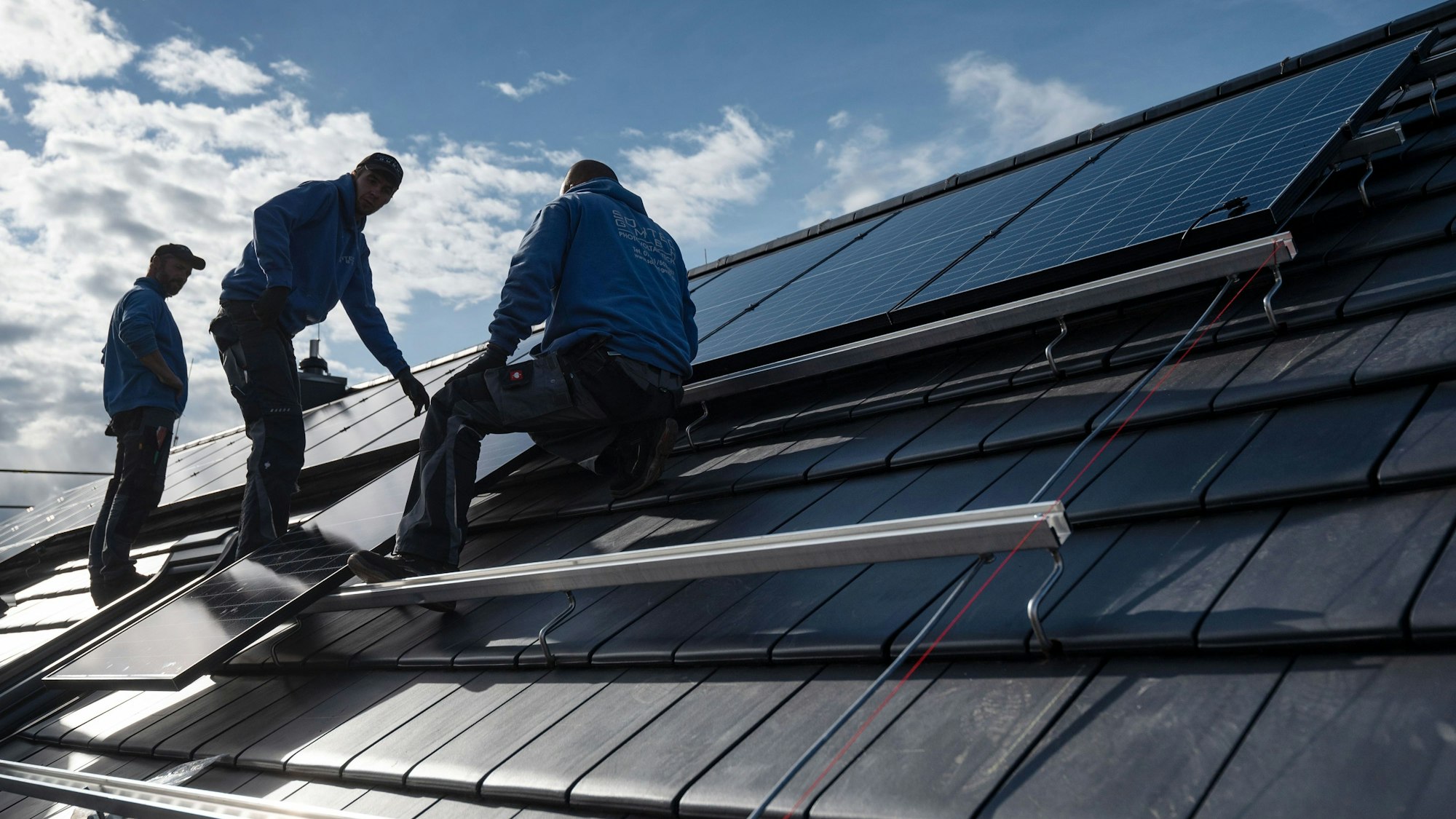 Dachdecker montieren Photovoltaikmodule auf dem Dach eines Wohnhauses.
