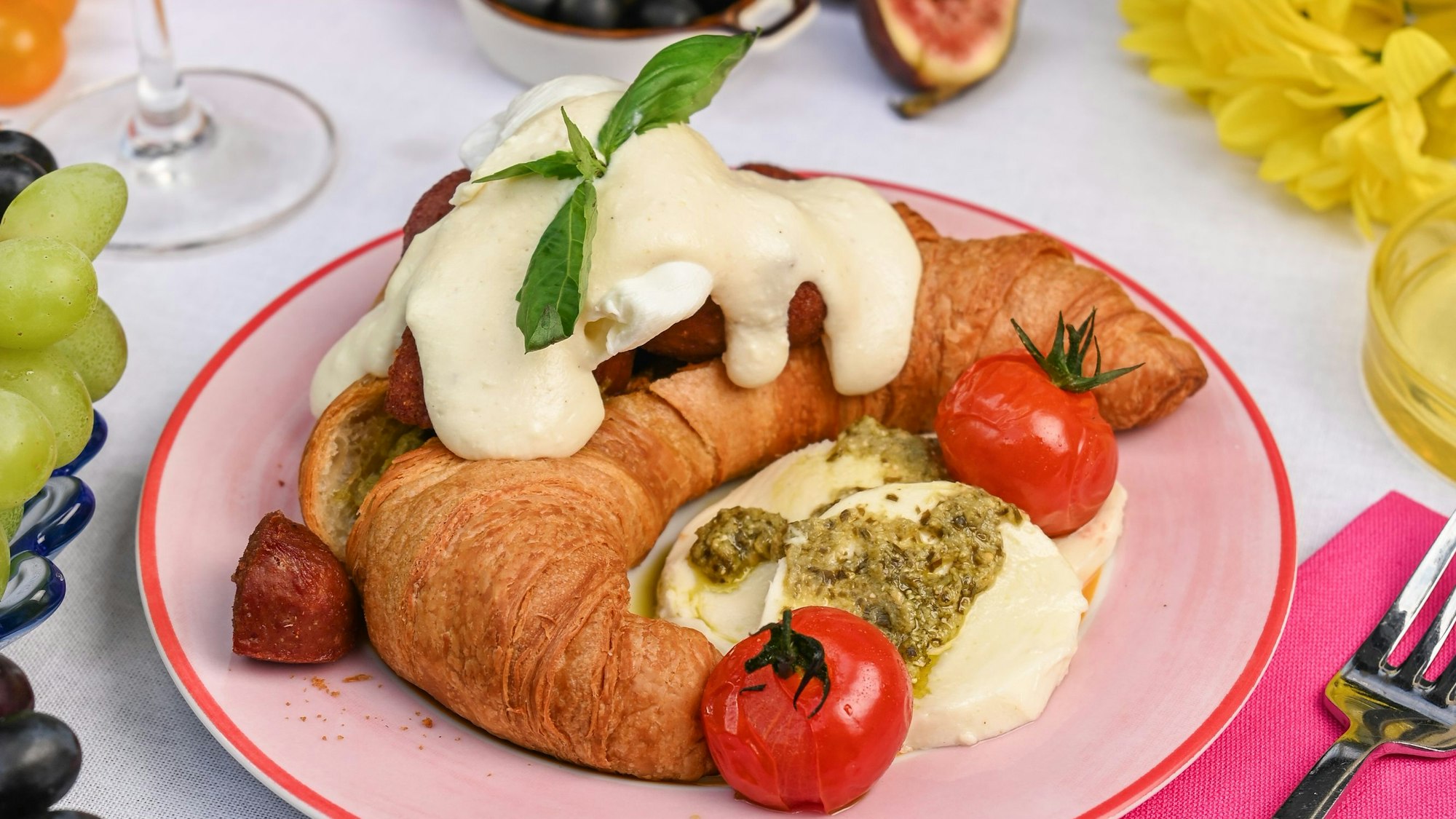 „Sucuk in Napoli“ - ein Croissant mit Basilikumpesto, Sucuk, pochiertem Ei, Ricotta-Béchamel, Mozzarella-Kugeln, confierten Tomaten und Basilikum.