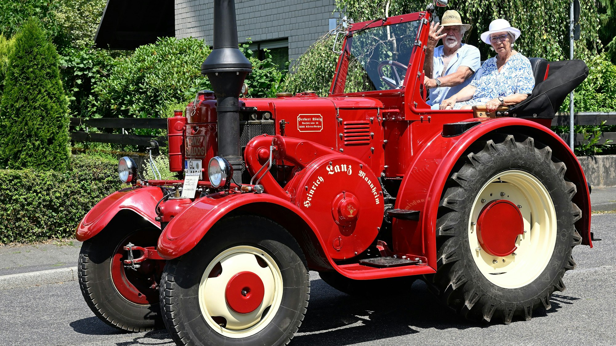 Zwei Menschen fahren auf einem roten Trecker.