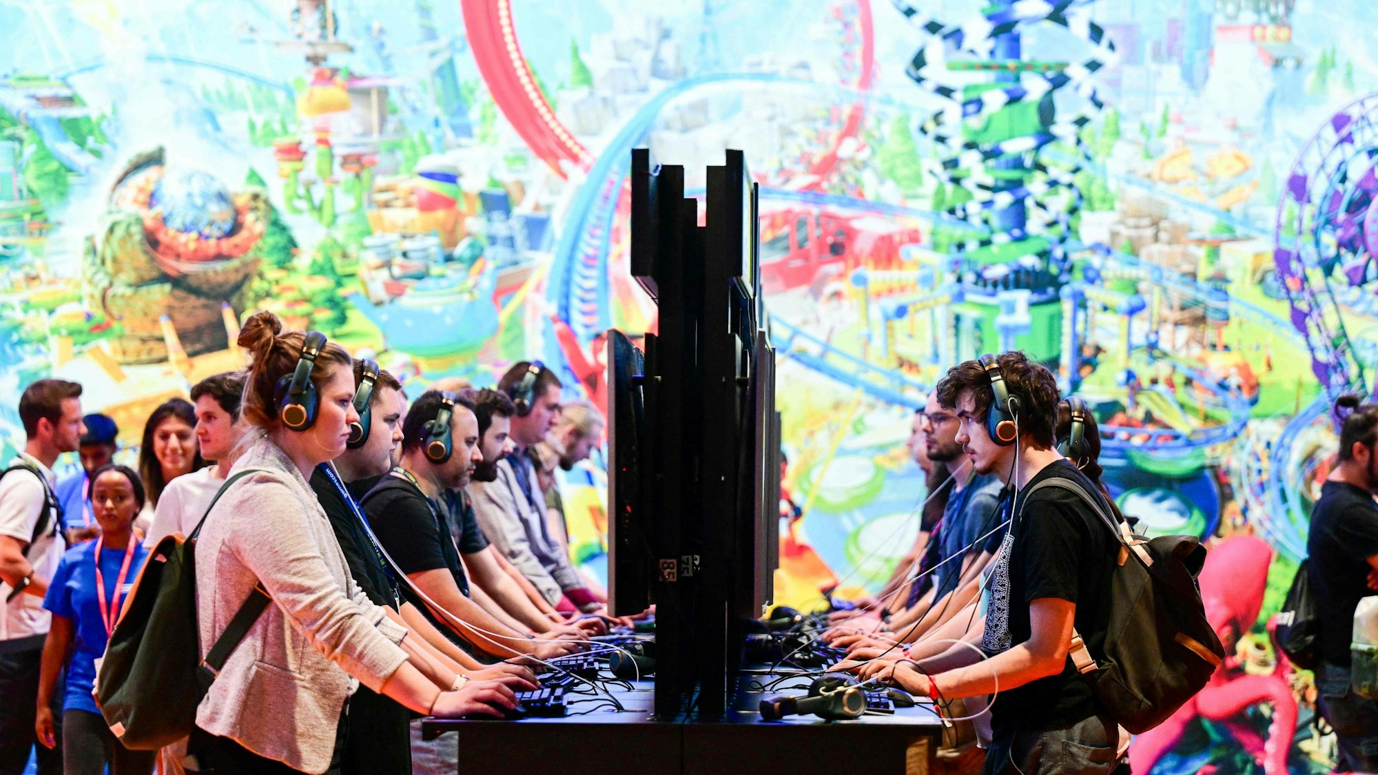 Mehrere Videospieler stehen nebeneinander und gegenüber. Alle gucken konzentriert in Monitoren.