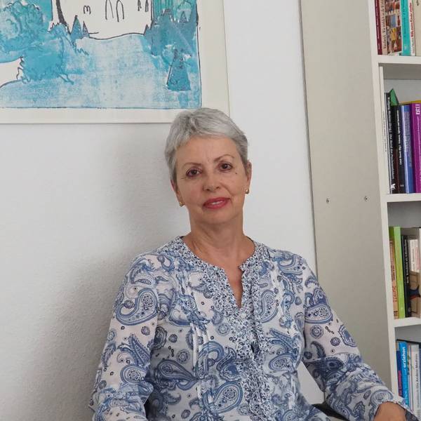 Eine Frau sitzt neben einem Bücherregal.