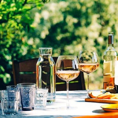 Roséwein im Glas und in der Flasche auf einem sommerlich gedeckten Tisch im Grünen