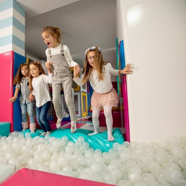 Gruppe von glücklichen kleinen Mädchen, die in eine Ballgrube springen.