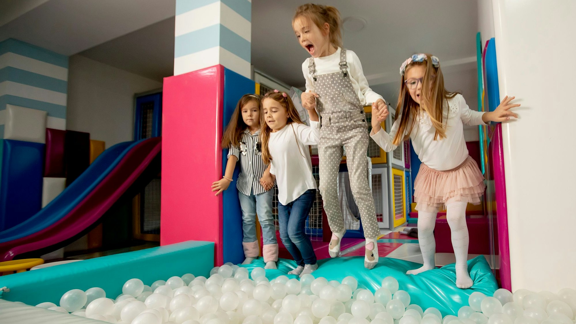 Gruppe von glücklichen kleinen Mädchen, die in eine Ballgrube springen.