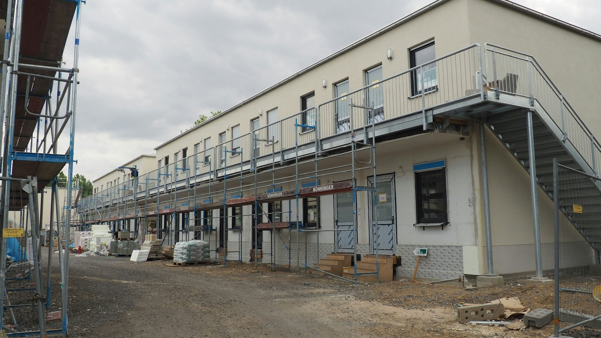 Auf einer Baustelle entstehen zweistöckige Gebäude, die zum Teil noch eingerüstet sind.