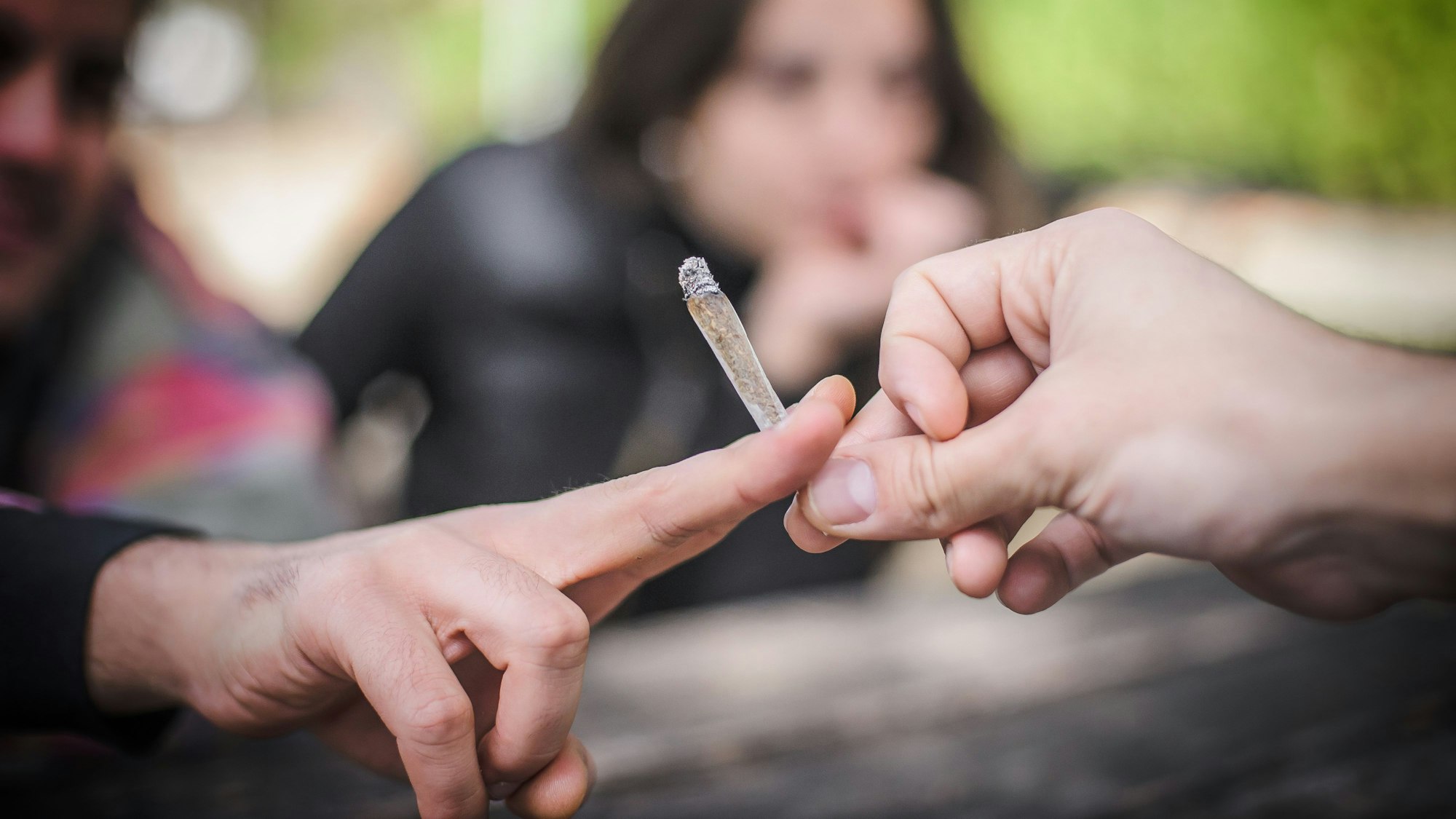 Zwei Menschen teilen sich einen Joint.