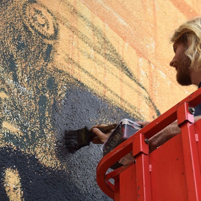 Der Künstler Lukas Zimmermann bemalt die Fassade der Swistbachschule.