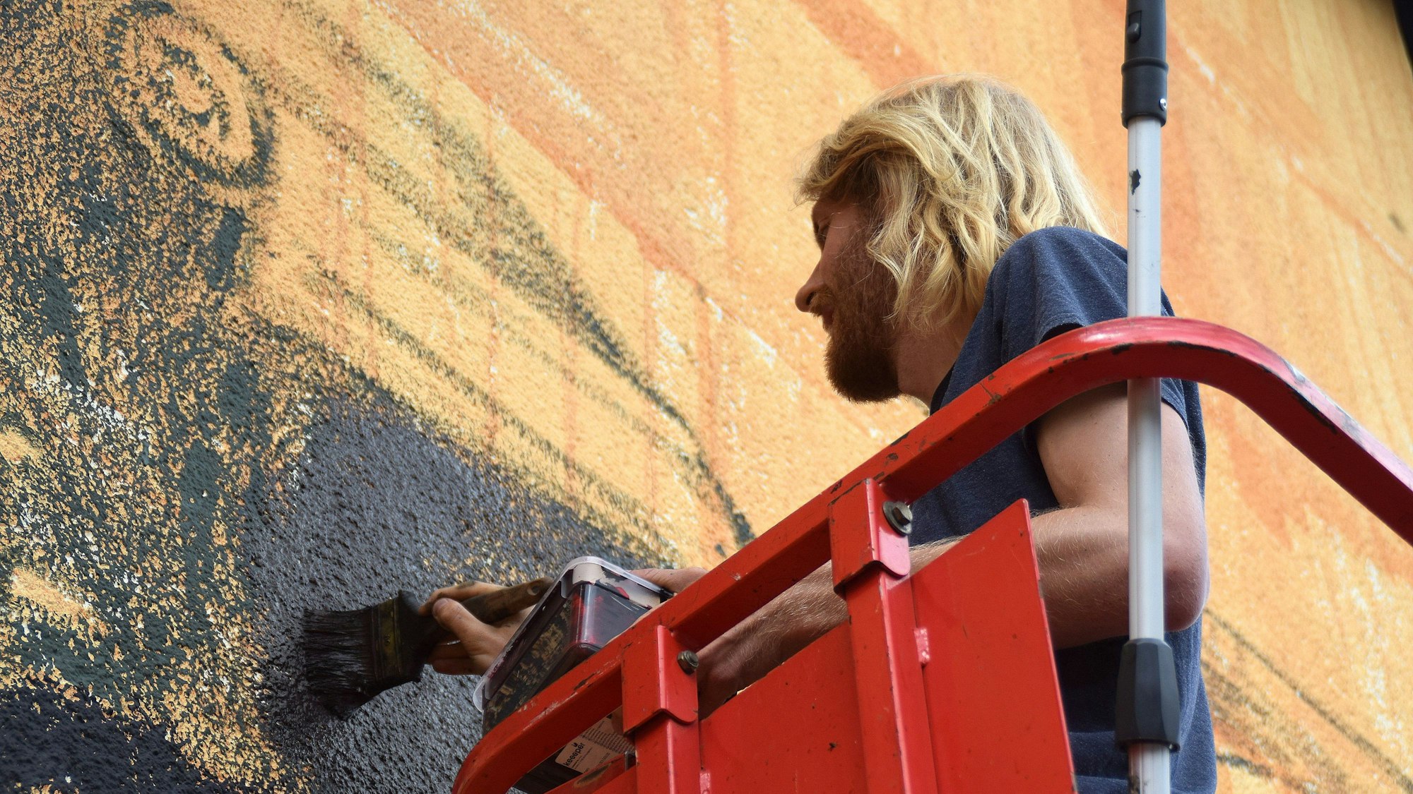 Der Künstler Lukas Zimmermann bemalt die Fassade der Swistbachschule.