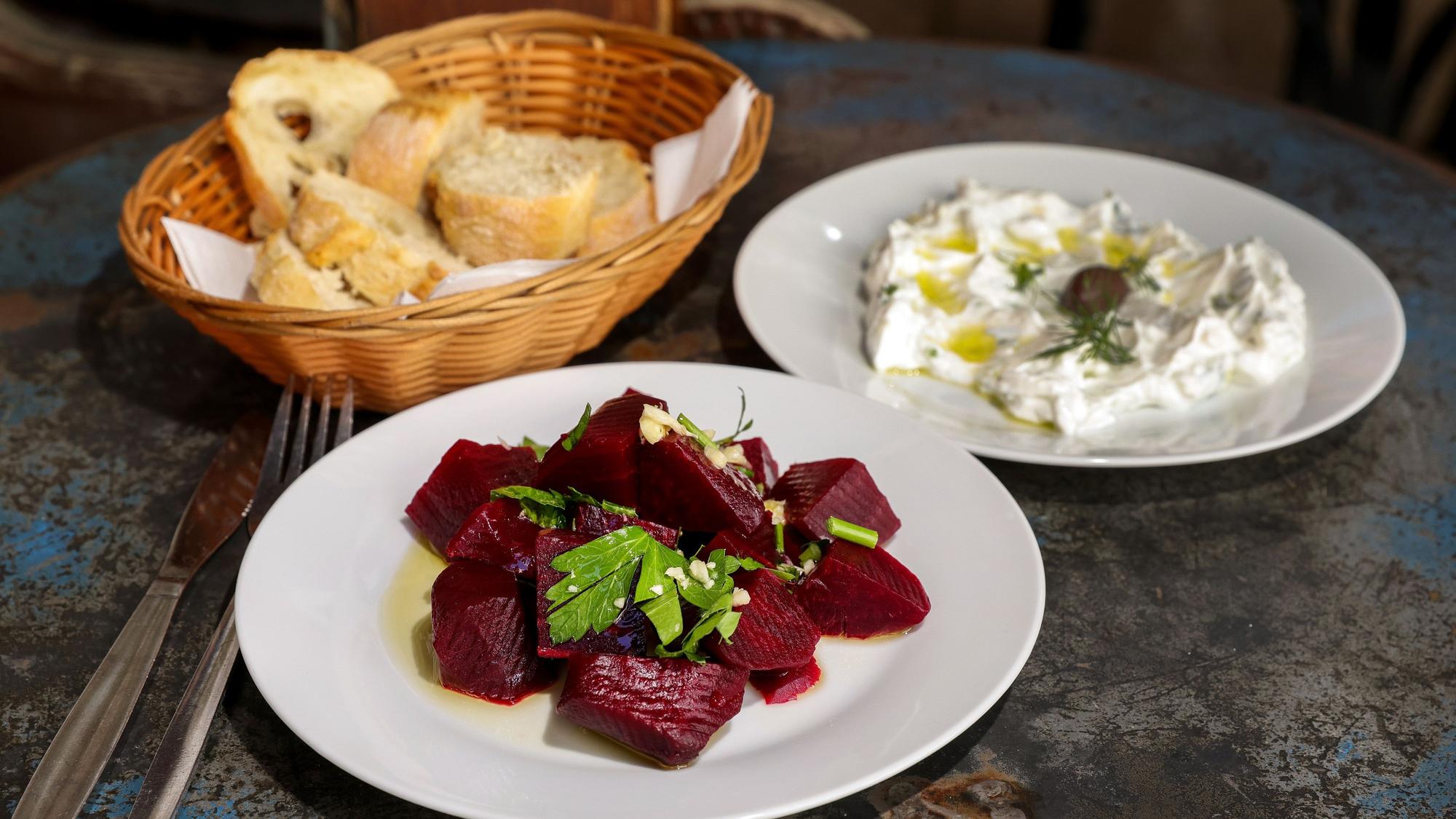 Rote-Bete-Salat Tsatsiki und Brot im Korb stehen auf einem Tisch.