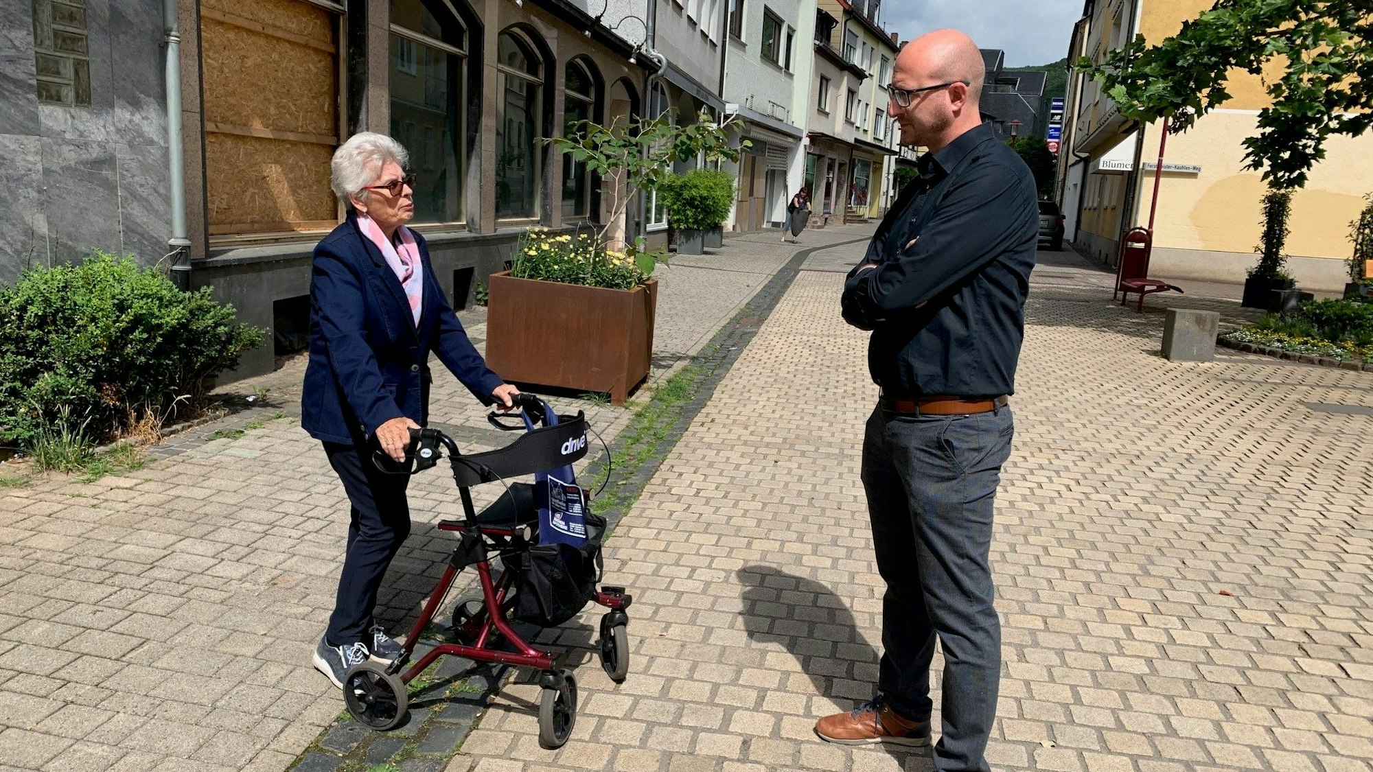 In der Gemünder Fußgängerzone spricht Bürgermeister Ingo Pfennings mit Karin Emunds, die mit ihrem Rollator unterwegs ist.