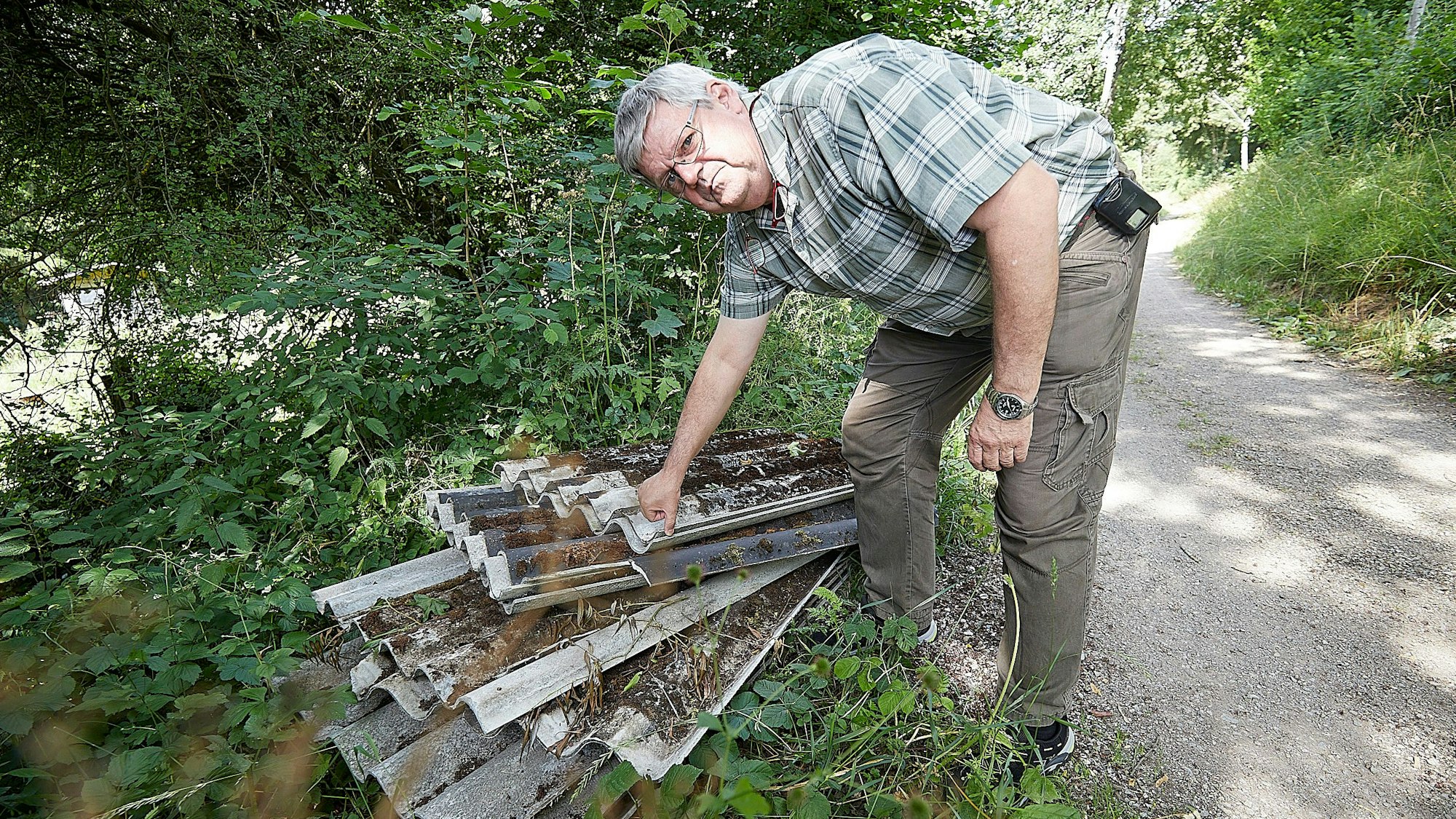 Harald Heinen sieht sich die am Wegesrand abgelegten Platten an.