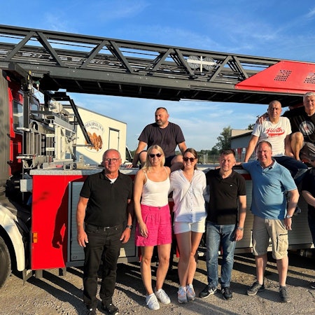 Eine Gruppe von Menschen vor einem Feuerwehrwagen.