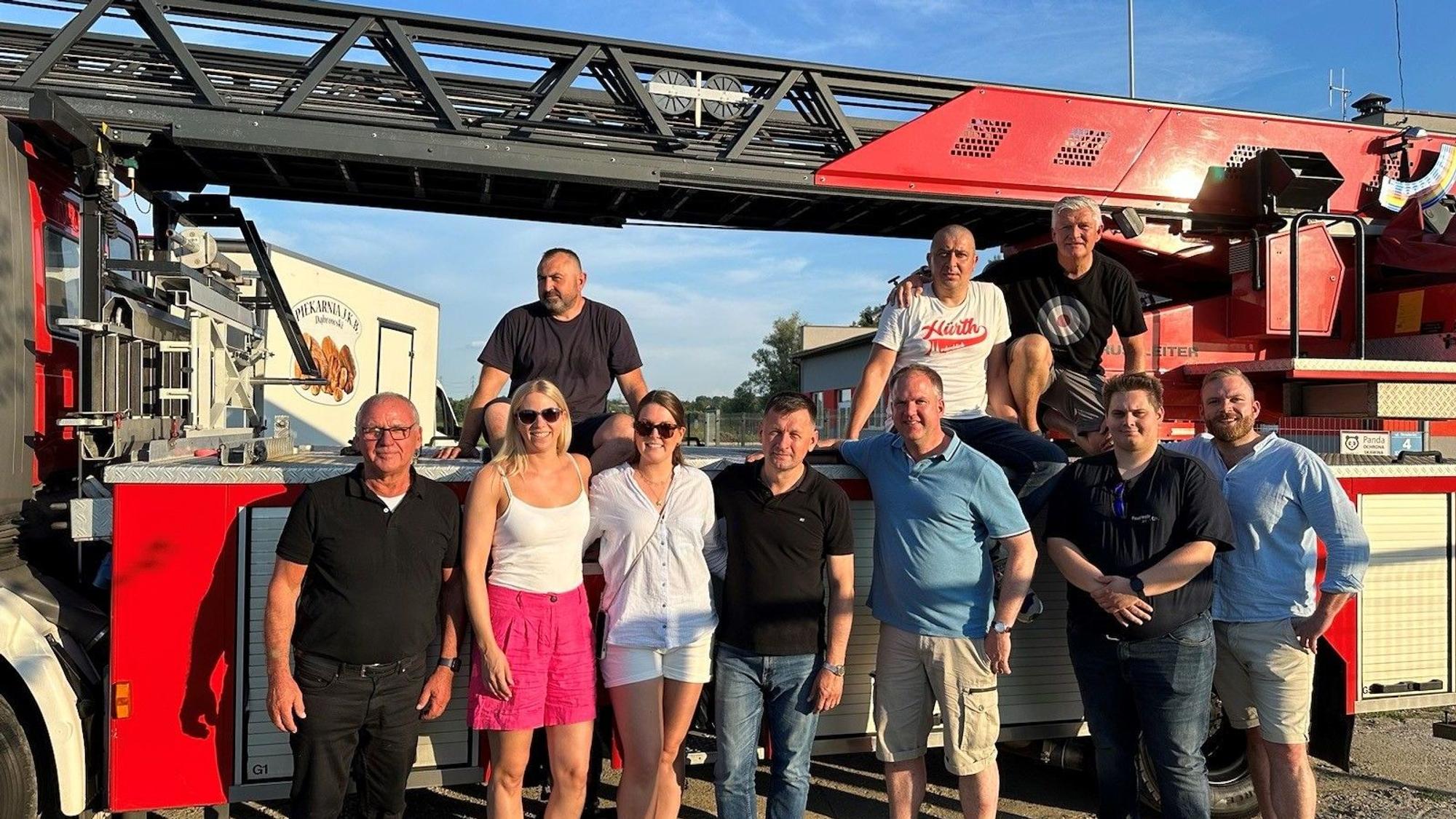 Eine Gruppe von Menschen vor einem Feuerwehrwagen.