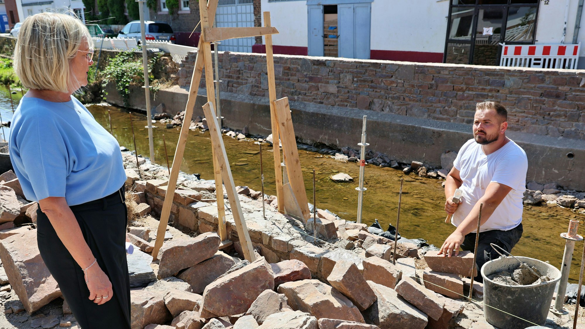 Bürgermeisterin Sabine Preiser-Marian unterhält sich mit einem der Arbeiter, der die Erftmauern wieder aufbaut.