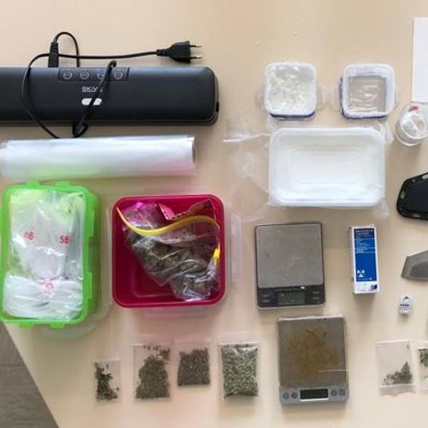 Die beschlangnahmten Gegenstände der Polizei sind auf einem Tisch ausgebreitet, darunter eine Machete, Marihuana und Amphetamine.
