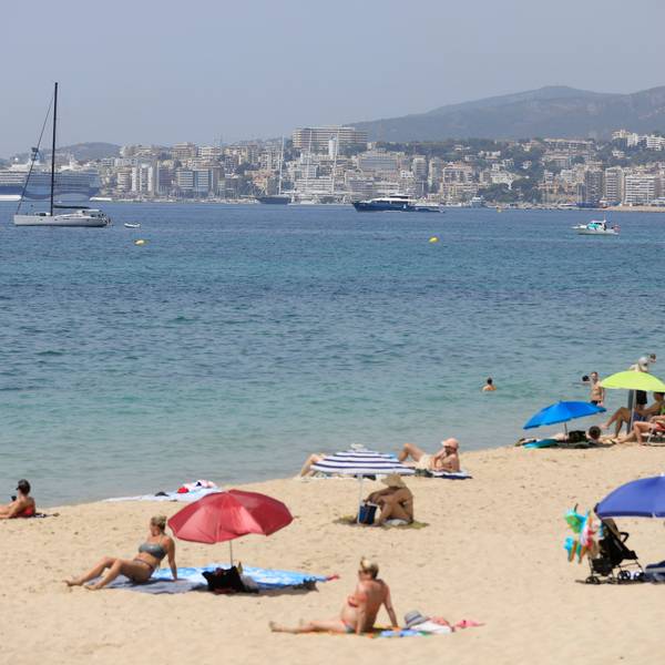 08.07.2023, Spanien, Palma: Menschen sonnen sich und benutzen Sonnenschirme am Strand Can Pere Antoni in Palma während einer Hitzewelle