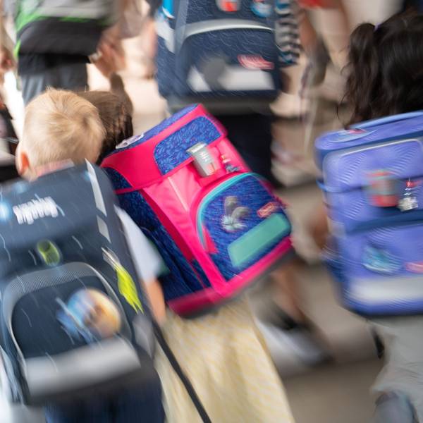 Schüler gehen während einer Einschulungsfeier der ersten Klasse zu ihrem Klassenraum.