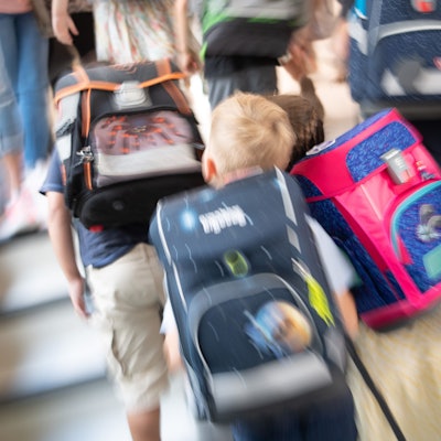 Schüler gehen während einer Einschulungsfeier der ersten Klasse zu ihrem Klassenraum.