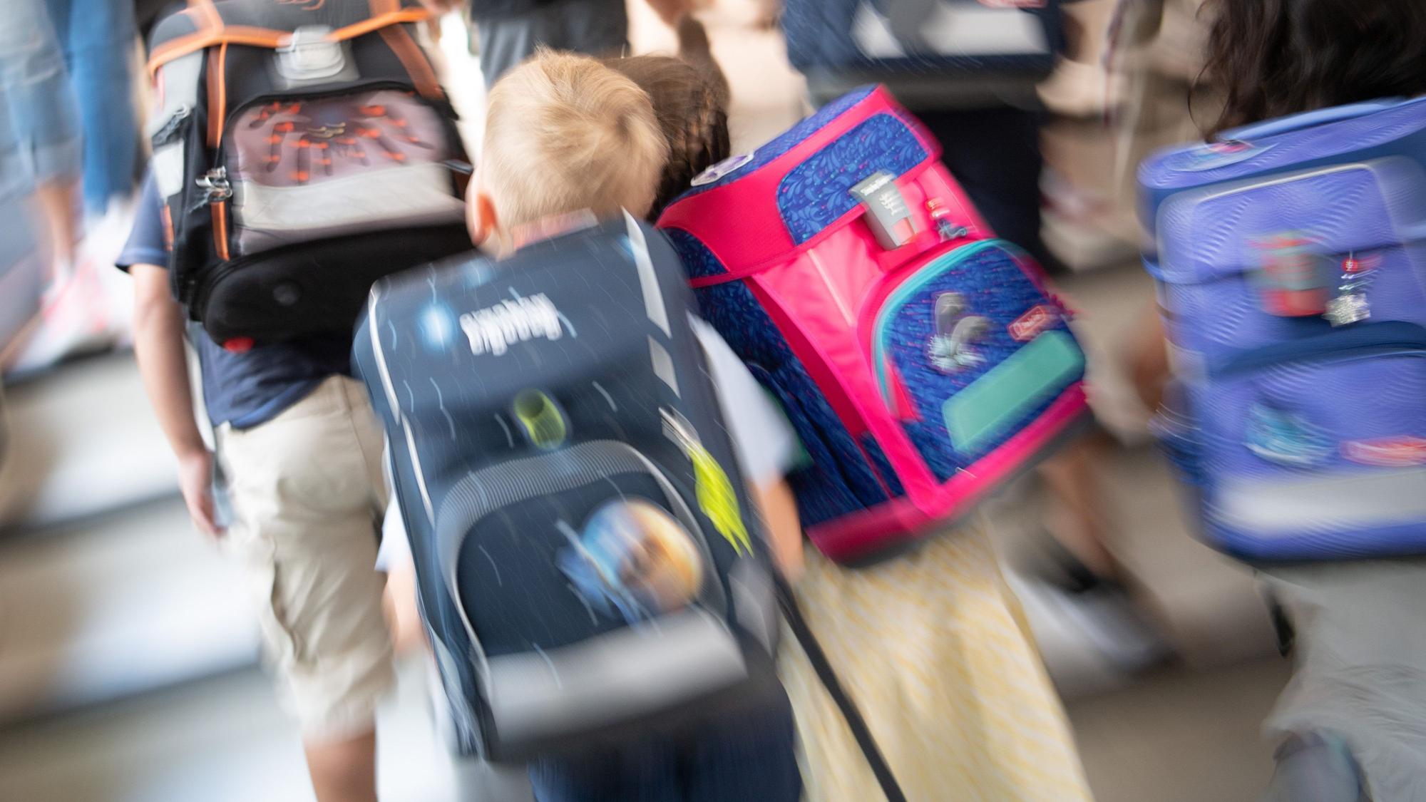 Schüler gehen während einer Einschulungsfeier der ersten Klasse zu ihrem Klassenraum.