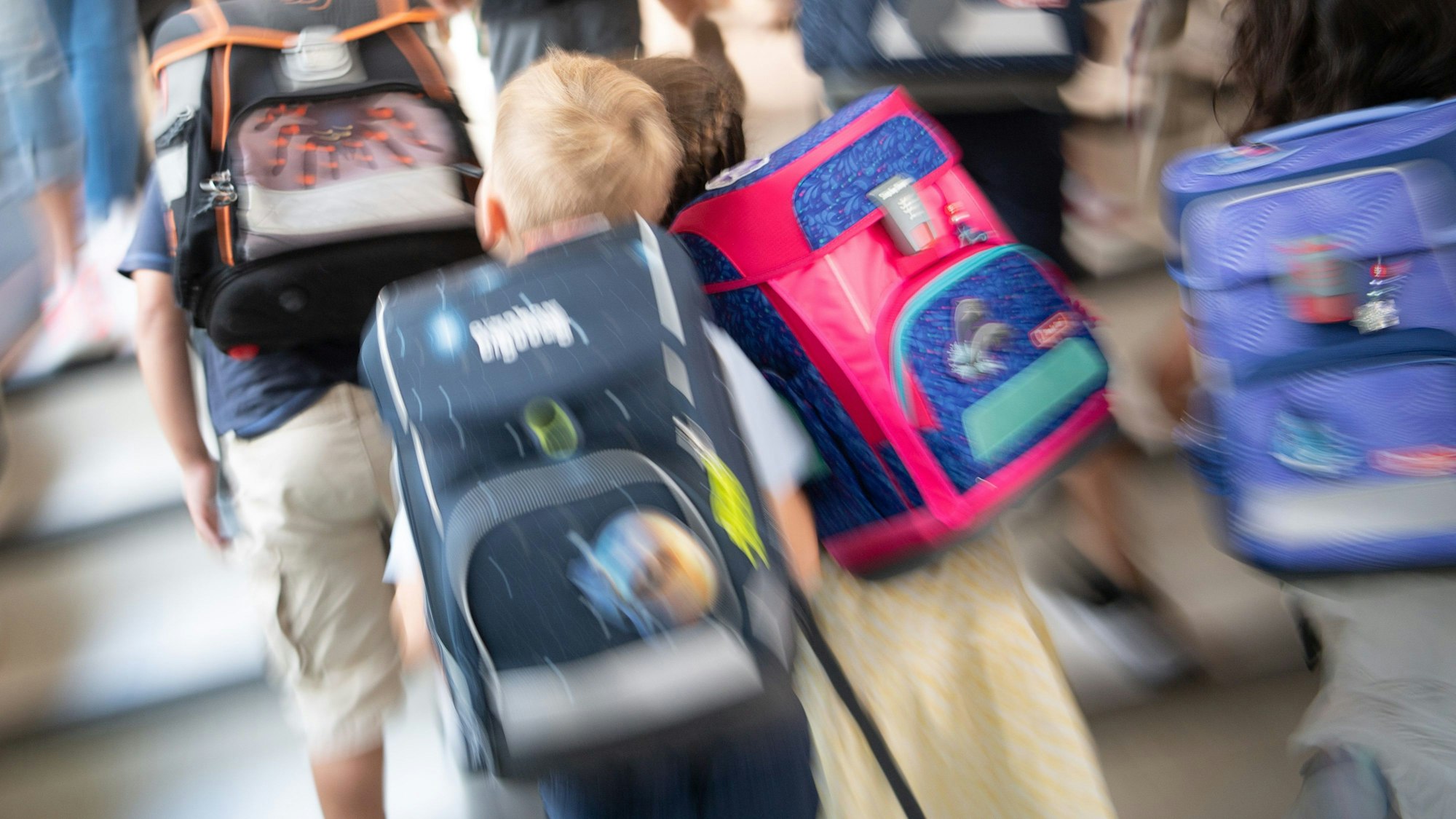 Schüler gehen während einer Einschulungsfeier der ersten Klasse zu ihrem Klassenraum.
