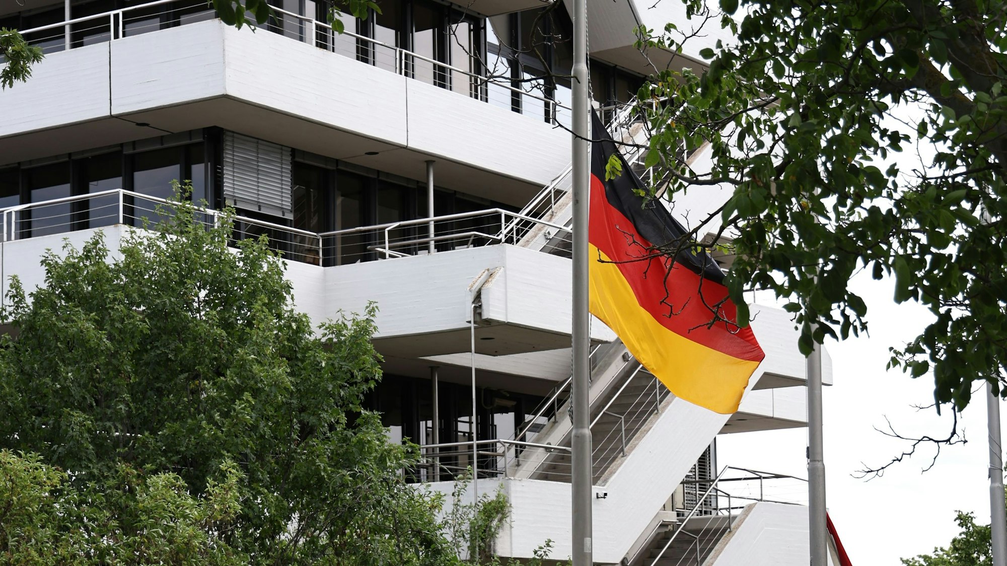 Eine Deutschlandflagge weht an einem Fahnenmast, im Hintergrund ist das Euskirchener Kreishaus zu sehen.