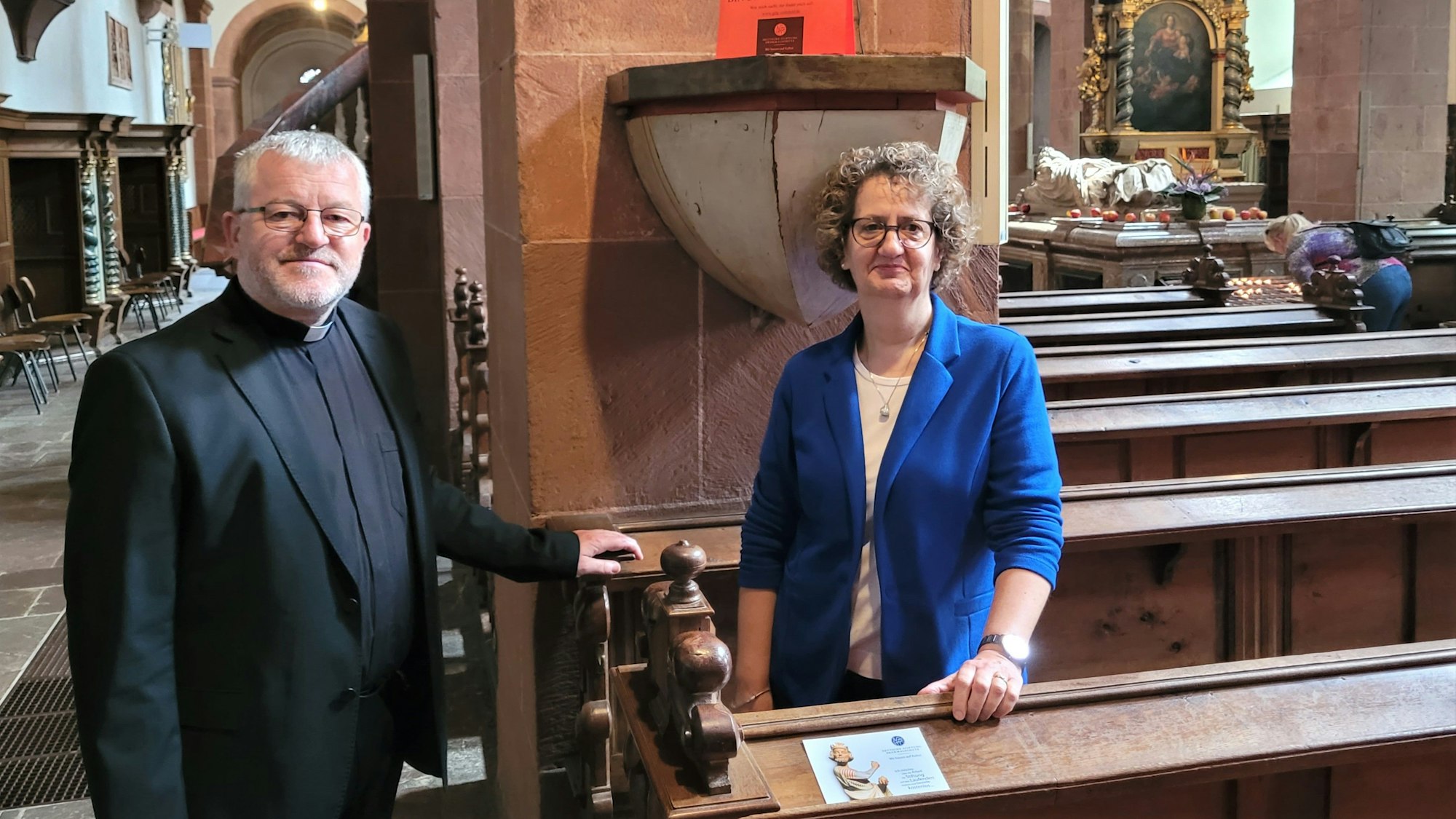 Ein Pfarrer und eine Frau stehen in einer Kirche.