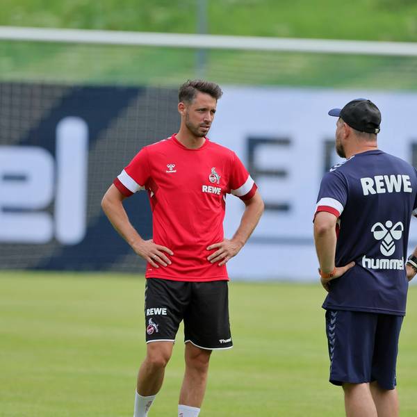 Mark Uth steht mit Steffen Baumgart auf dem Rasen und unterhält sich.
