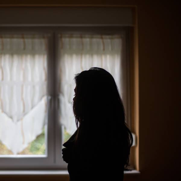 Eine Frau steht vor einem Fenster.