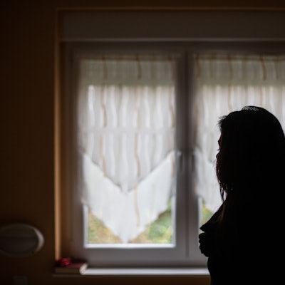 Eine Frau steht vor einem Fenster.