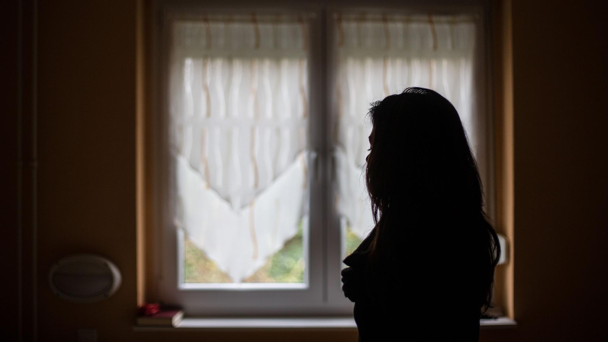 Eine Frau steht vor einem Fenster.